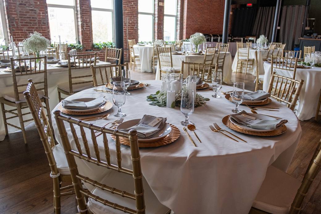A set reception table with gold chairs, glassware and copper chargers